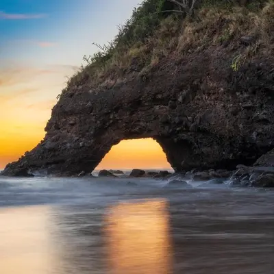 an arch in the rocks on the beach at sunset at Bella Vista Hotel Boutique in San Miguel