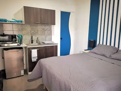 a bedroom with a bed and a kitchen with blue walls at Apartamento privado, Miramonte, San Salvador in San Salvador