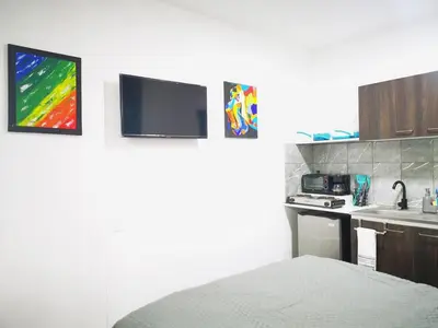 a room with a bed and a kitchen with a tv at Suite privada de 1 habitacion en San Salvador in San Salvador