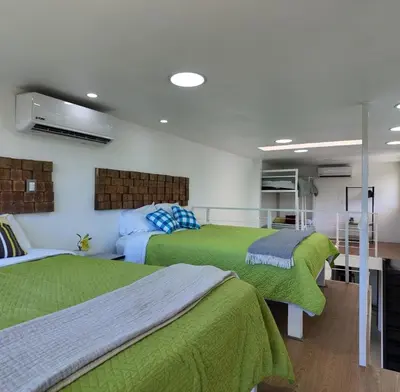 two beds in a room with green blankets at Las Terrazas Suites Studio Apartment in San Salvador