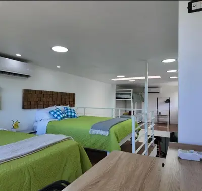 two beds in a room with green sheets at Las Terrazas Suites Studio Apartment in San Salvador