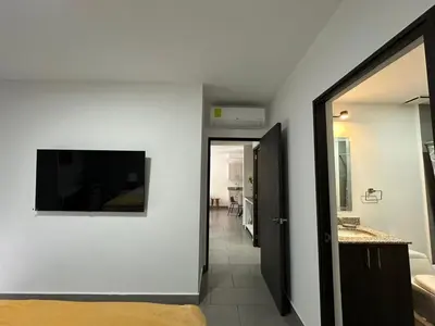 a room with a television on the wall and a hallway at Apartamento Casas del Árbol Condado Santa Rosa Santa Tecla in Nanastepeque