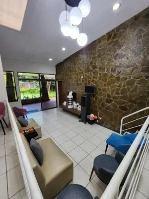 a living room with couches and chairs and a stone wall at La Mochila Urbana2 in San Salvador