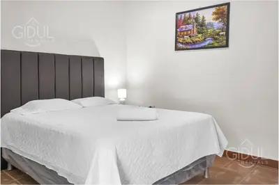 a bedroom with a bed with white sheets and a picture on the wall at Cozy Bedroom in a coffee farmn in Coatepeque Lake in Santa Ana