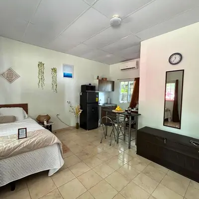a bedroom with a bed and a table and a kitchen at La ceiba surf in El Sunzal