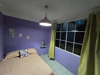 a purple bedroom with a bed and a window at central and private apartment in Santa Ana