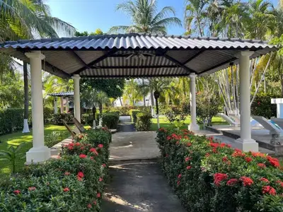 a pavilion with flowers in a park with palm trees at Pool • Resort Access • Game Room • Fire Pit in Los Cóbanos