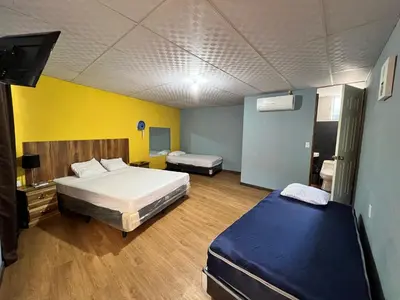 a bedroom with two beds and a tv in it at Hostal Noche de Luna in San Salvador