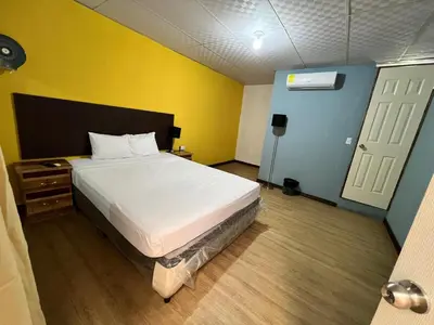 a bedroom with a white bed and a yellow wall at Hostal Noche de Luna in San Salvador